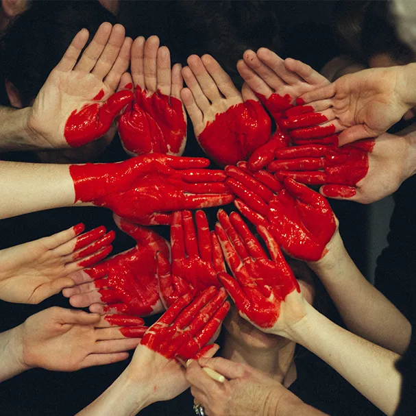 Many hands painted red, arranged together in the shape of a heart